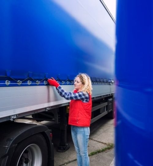 female-truck-driver-checking-vehicle-tightening-truck-tarpaulin_342744-292